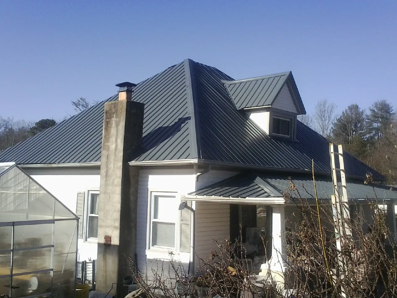 Dark blue standing seam metal roof on a white farmhouse with dormer — Slate & Tile Roof Repair by Roofing Brothers in Batesville