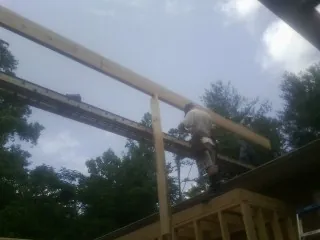 Carpenter setting a ridge beam over a new addition frame — Ice Dam Removal by Roofing Brothers in Batesville