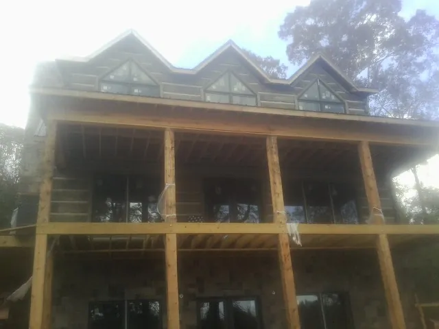 Dormers and porch framing on a large log home under construction — Roof Coating work by our crew in Batesville