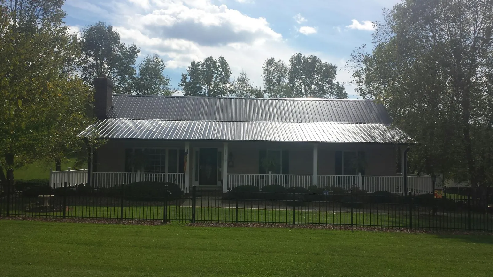 Gray metal roof on a brick ranch with a full width front porch — Gutter Guard Installation work by our crew in Batesville