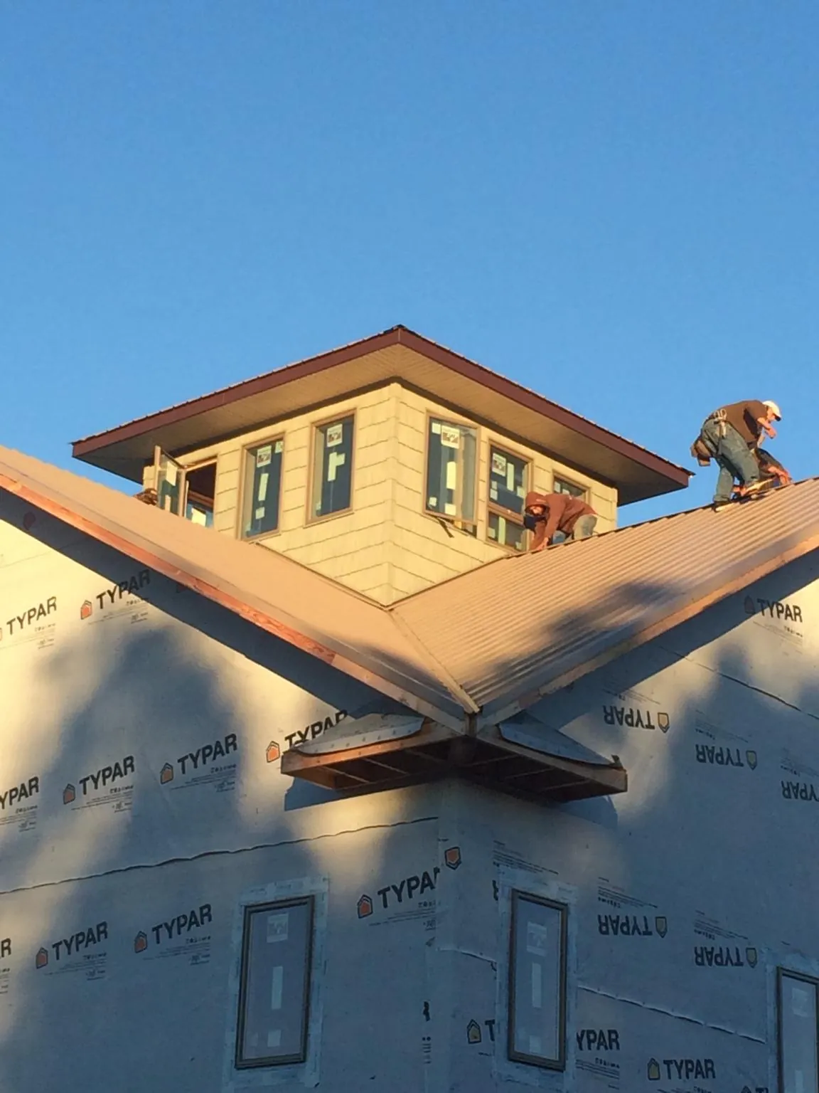 Roofers working around a rooftop cupola on a new metal roof at sunset — Roof Waterproofing in Batesville by Roofing Brothers